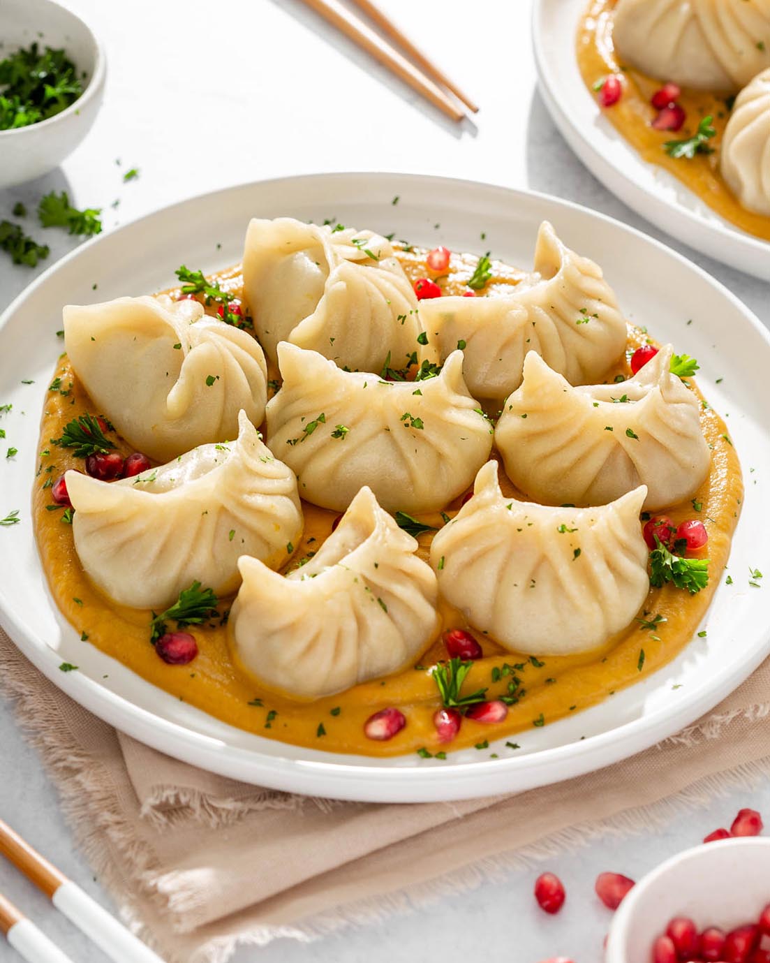 Up close of A plate of turkey dumplings sitting on butternut squash puree surrounded by table settings