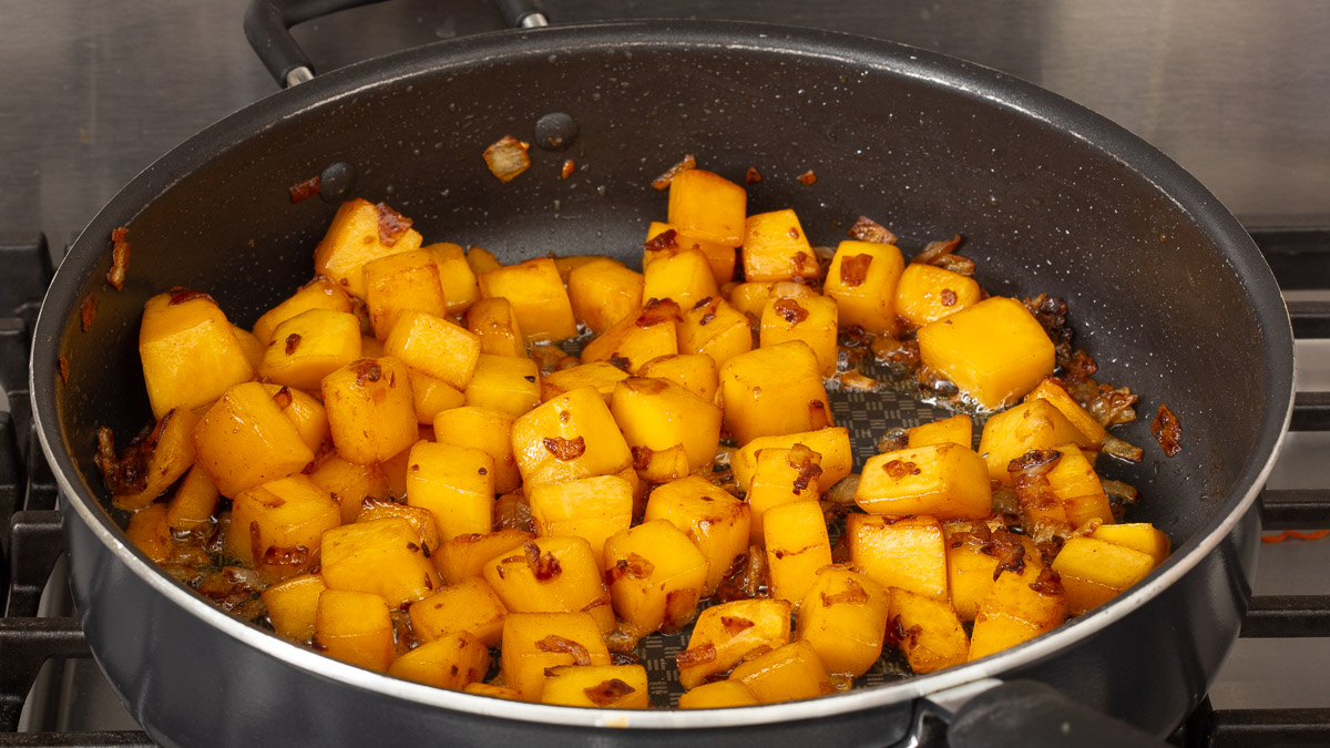 Cubed butternut squash cooking in a deep dish pan