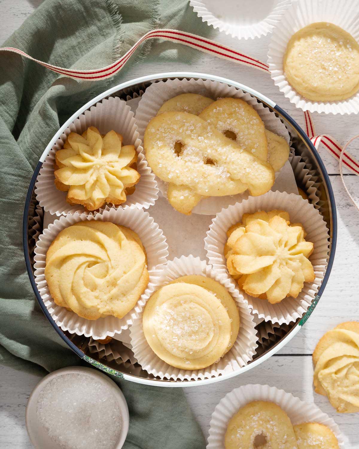 Looking down into a tin of homemade danish butter cookies with some taken out surrounding the tin.