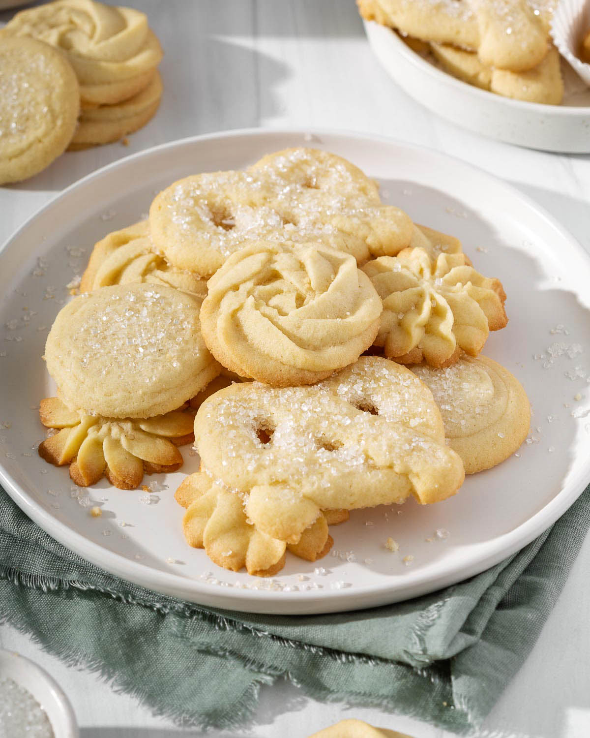 Up close of danish butter cookies piled onto a plate.