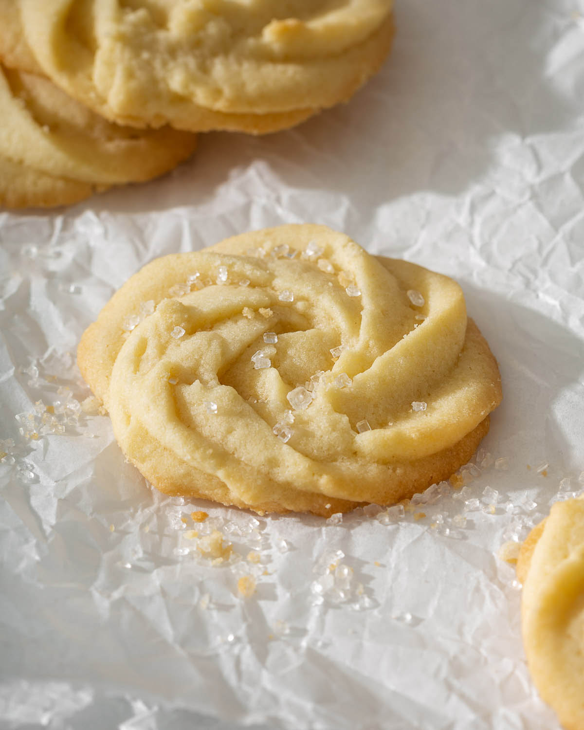 Up close of a danish butter cookie in a rose shape sitting on parchment paper.