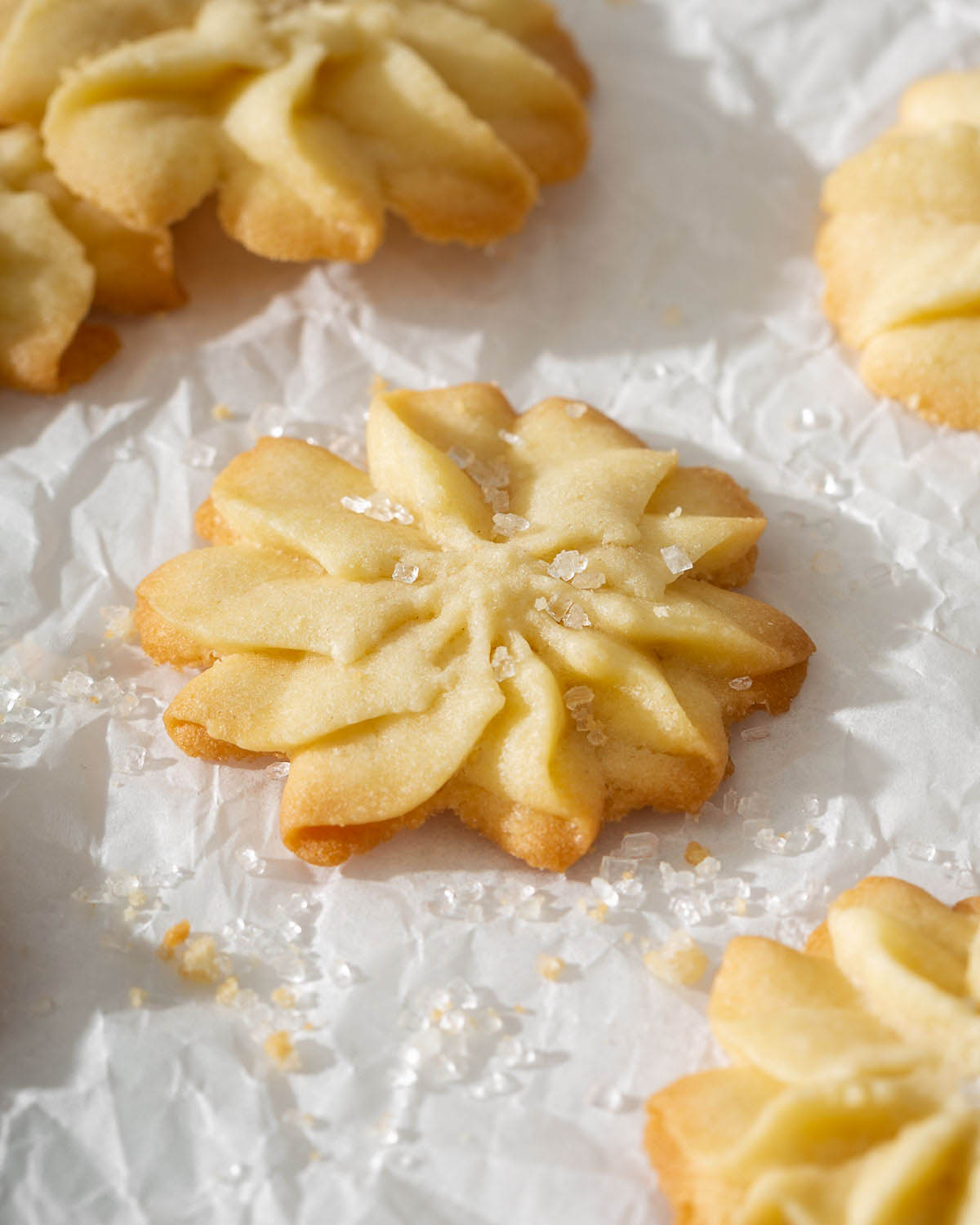 Up close of a danish butter cookie in a star shape sitting on parchment paper.
