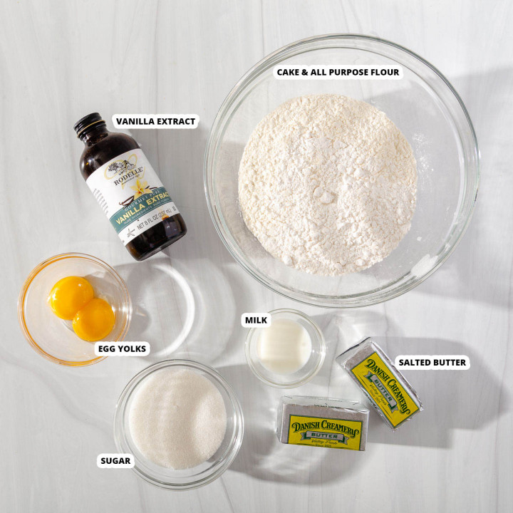 The ingredients for danish butter cookies laying on a surface with labels