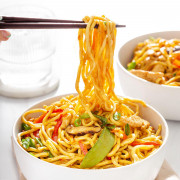 Up close of noodles being lifted from a bowl of lo mein