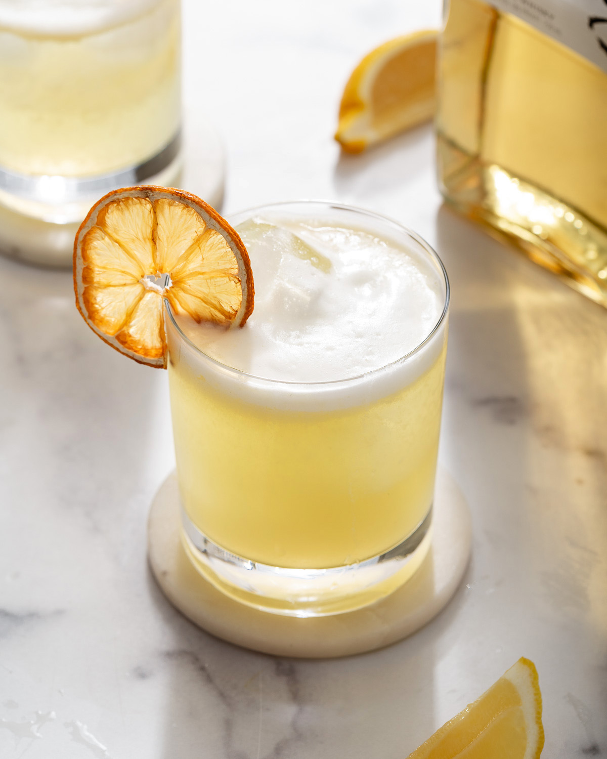 A Japanese yuzu whiskey sour in a rocks glass on a coaster.