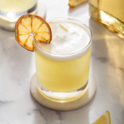 A Japanese yuzu whiskey sour in a rocks glass on a coaster up close.