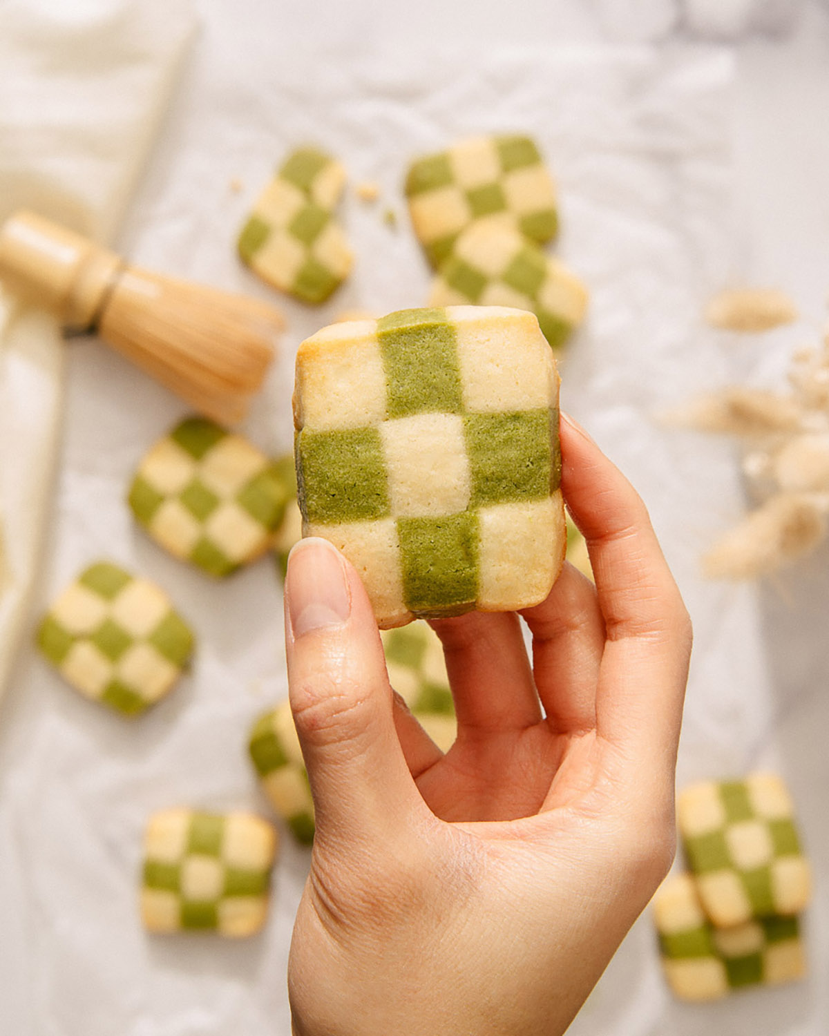 Someone lifting up a matcha checkerboard cookie