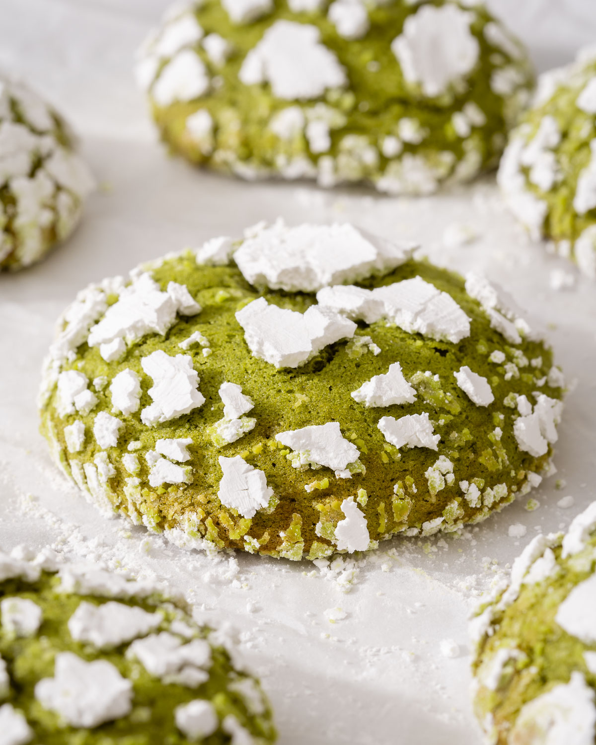 Up close of a matcha crinkle cookie on parchment paper