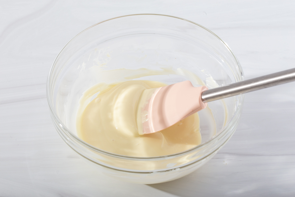 Mixing together the melted white chocolate and honey in a heat proof glass bowl.