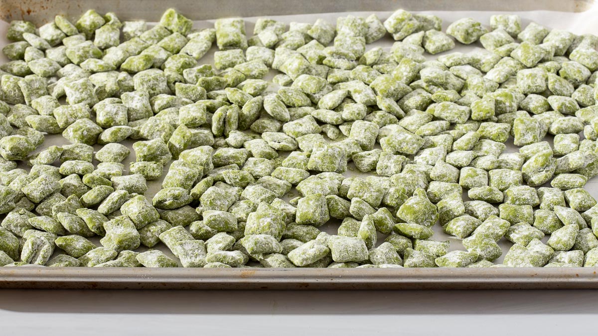 The completed matcha puppy chow tossed in powdered sugar and spread onto a parchment lined baking tray to cool and harden.