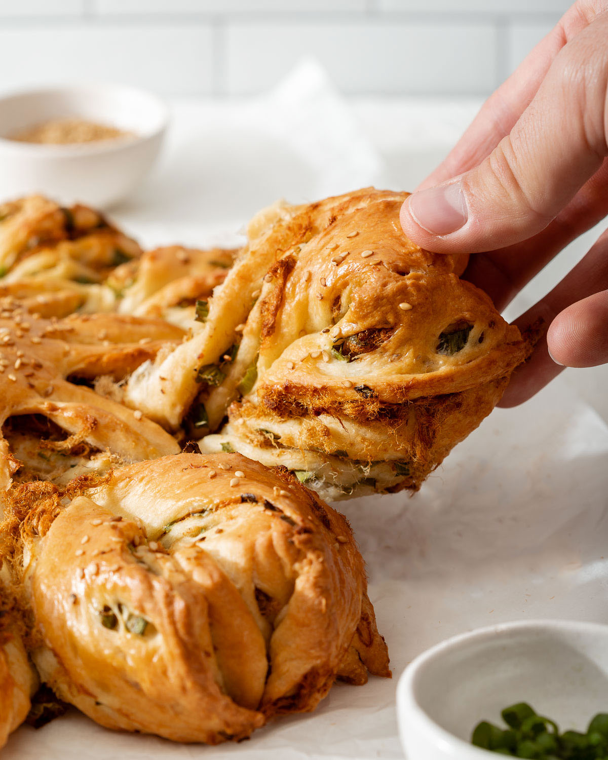 Someone pulling off an arm of freshly baked star bread.