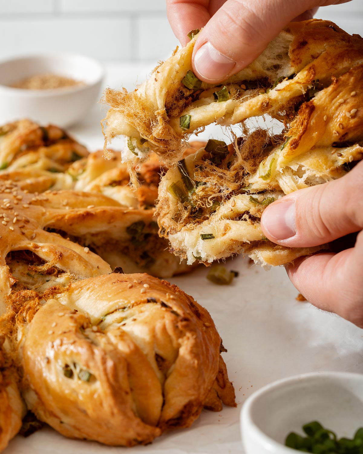 Someone pulling open an arm of star bread to see the pork floss and scallions inside.