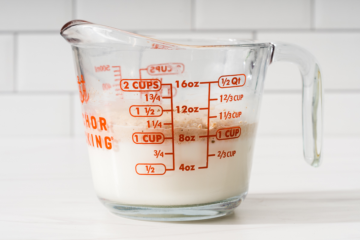 A glass measuring cup with freshly bloomed yeast in milk.