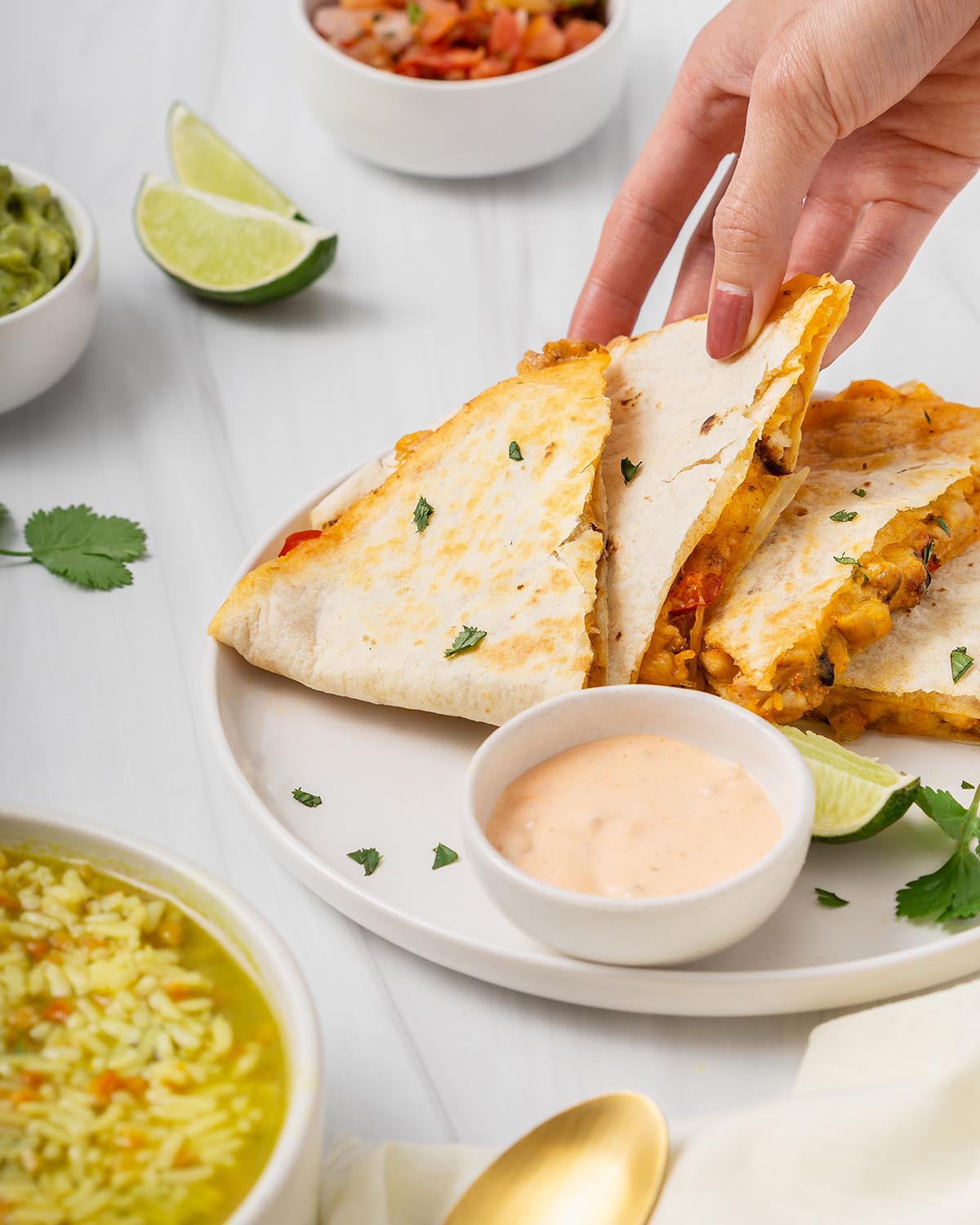 Someone lifting up a slice of quesadilla from a plate