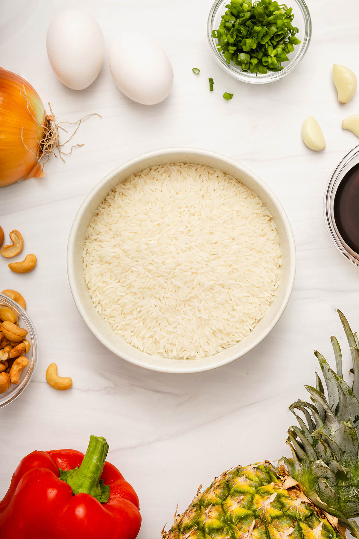 Looking down at the raw ingredients and jasmine rice in a bowl that is needing for fried rice.