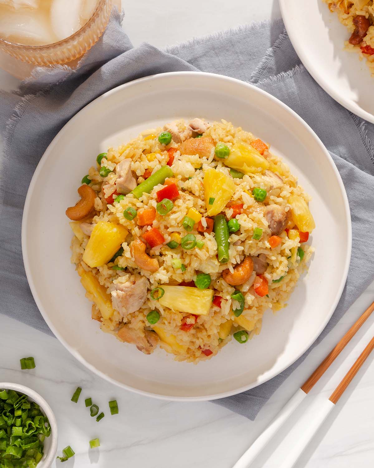 Looking down at a plate of pineapple fried rice with table settings surrounding it