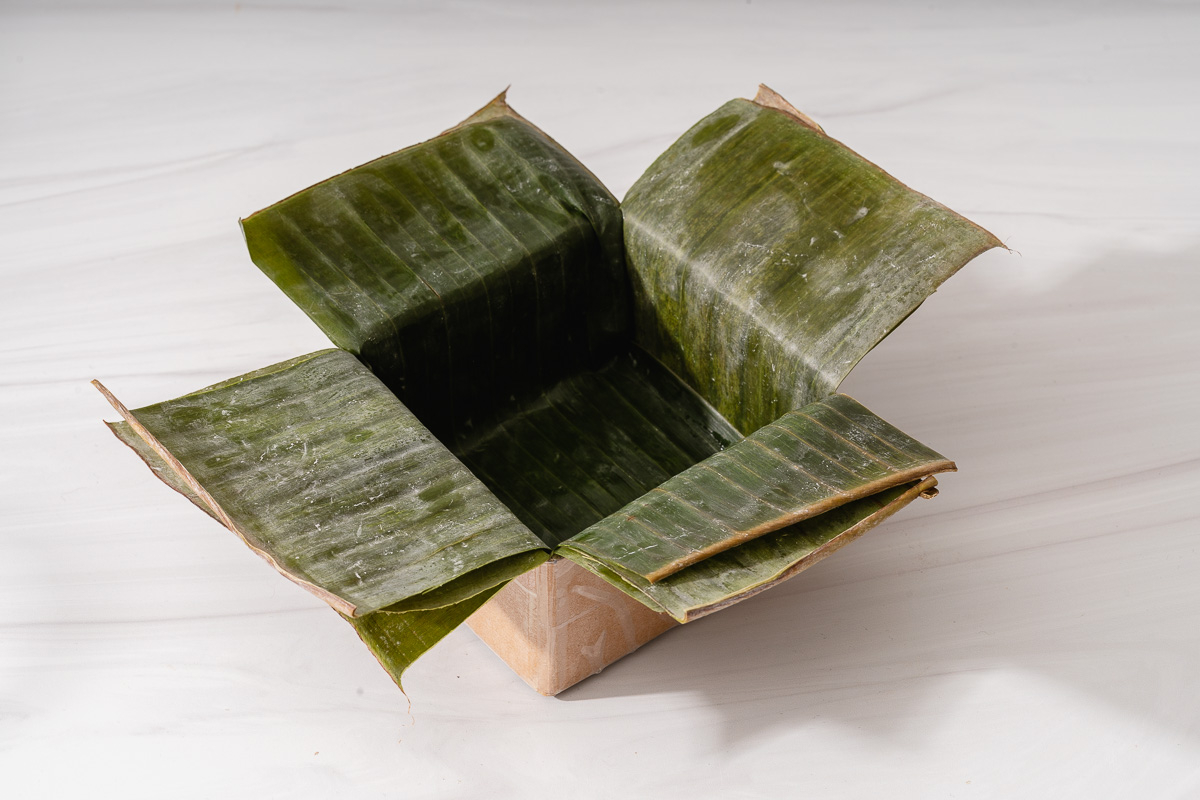 A ban chung cardboard mold lined with banana leaf strips.