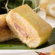 Up close of a sliced Vietnamese sticky rice cake for tet sitting on a banana leaf on a plate.