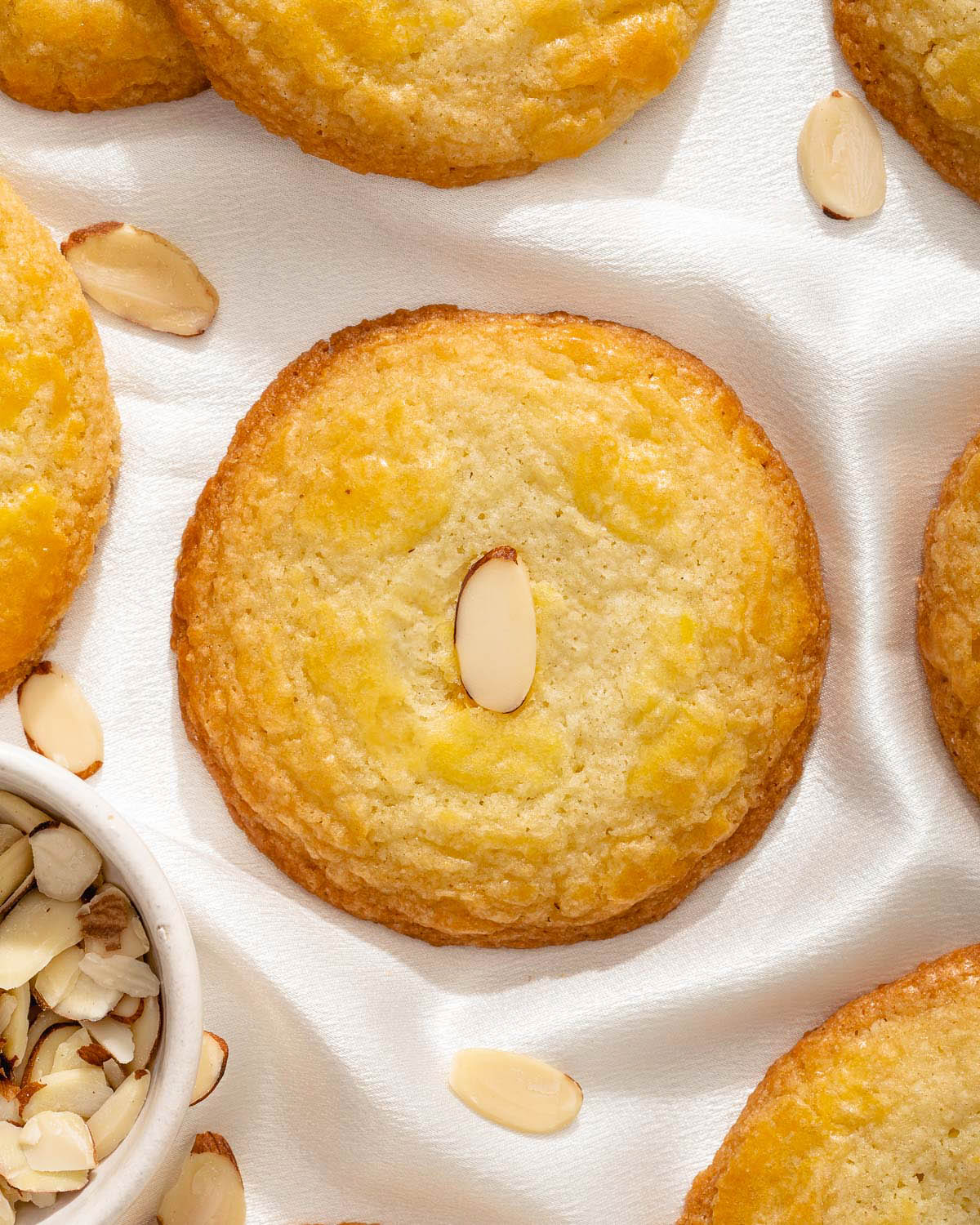 Looking down at scattered Chinese almond cookies and slivers of almonds on a table.