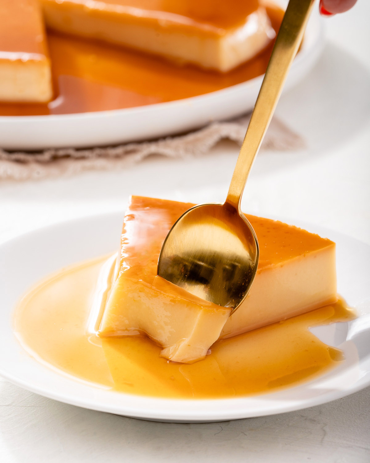 Up close of someone scooping a bite out of a slice of flan.