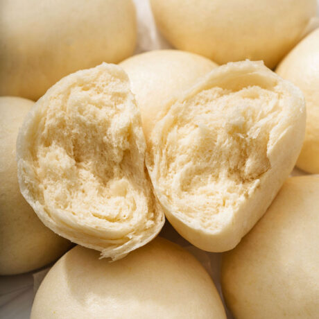 A torn open mantou Chinese steamed bun resting on more steamed buns.
