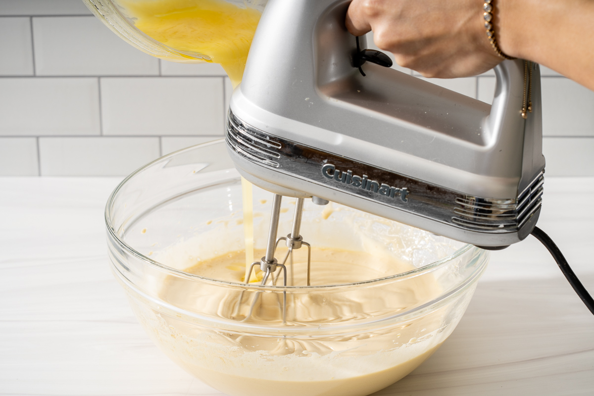 Slowly adding melted butter in liquid ingredients while mixing.