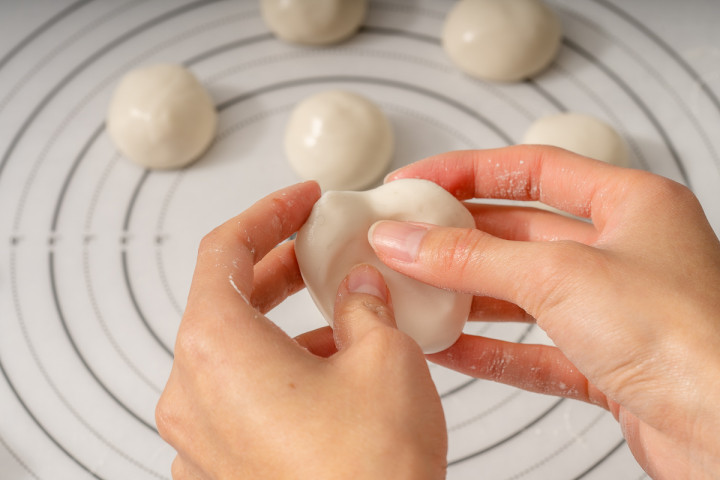 Preparing an indent in the dough ball to place paste filling.
