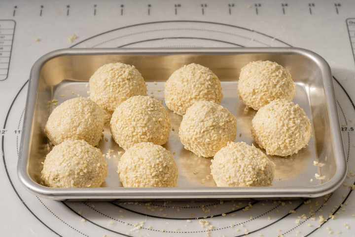 Red bean paste filled sesame balls on a tray ready to be fried.