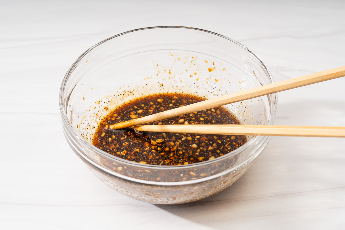 A glass bowl with Vietnamese shaking beef marinade mixed inside.