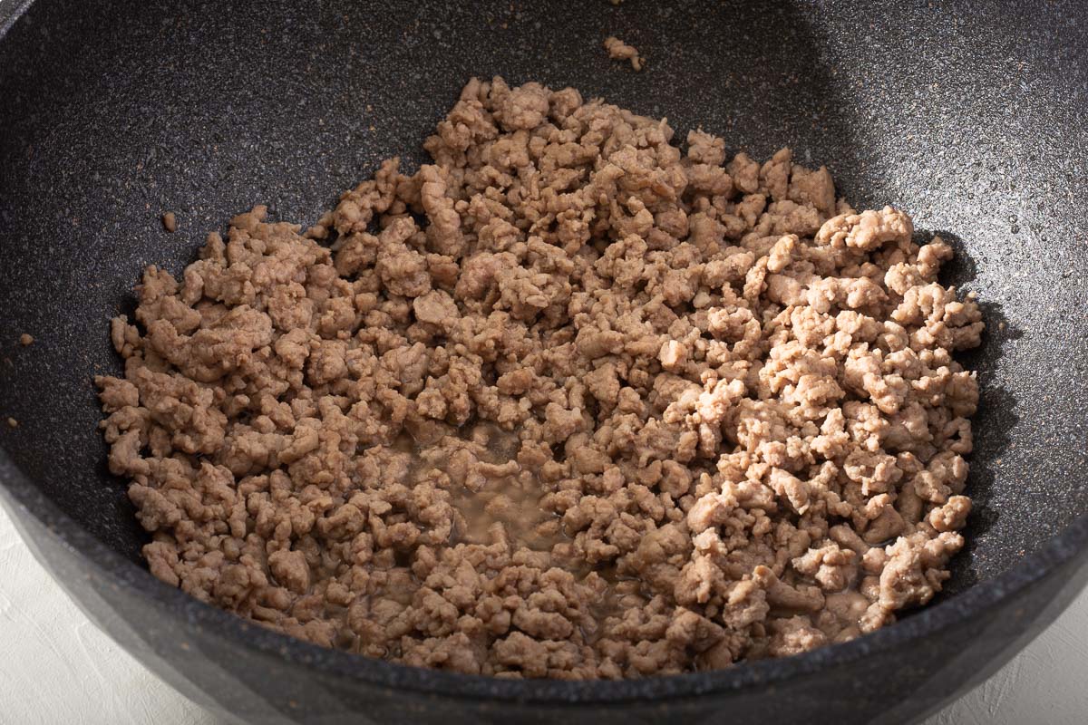 A wok with freshly cooked ground pork inside.