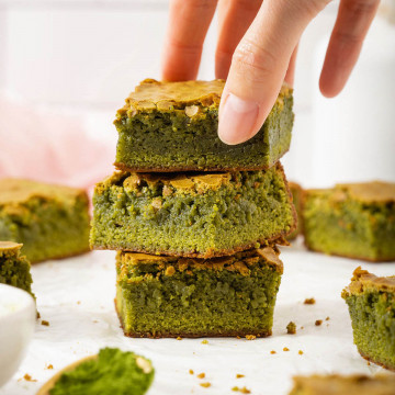 Up close of someone grabbing a matcha brownie from a stack.