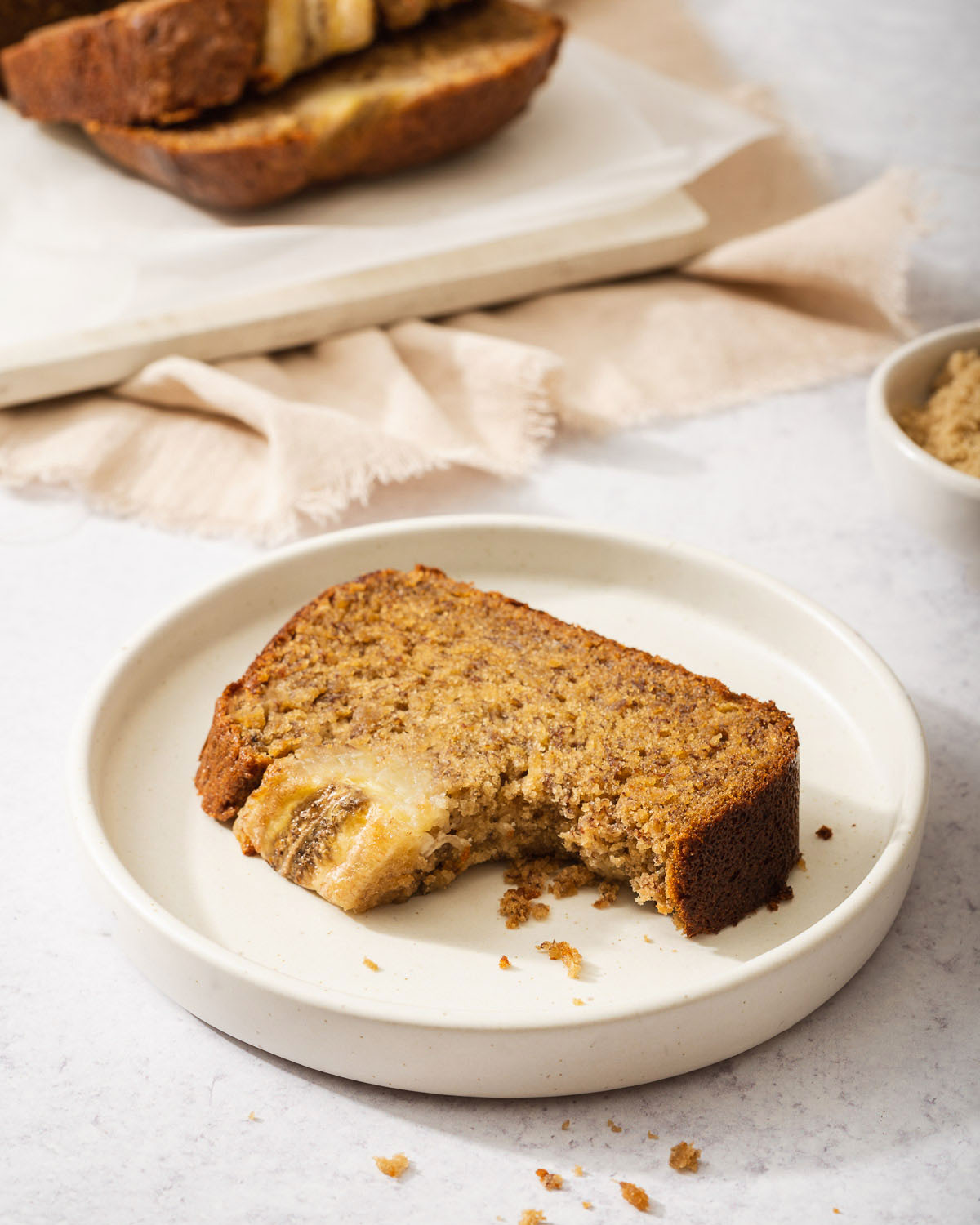 A slice of miso banana bread with a bite out of it on a small plate.