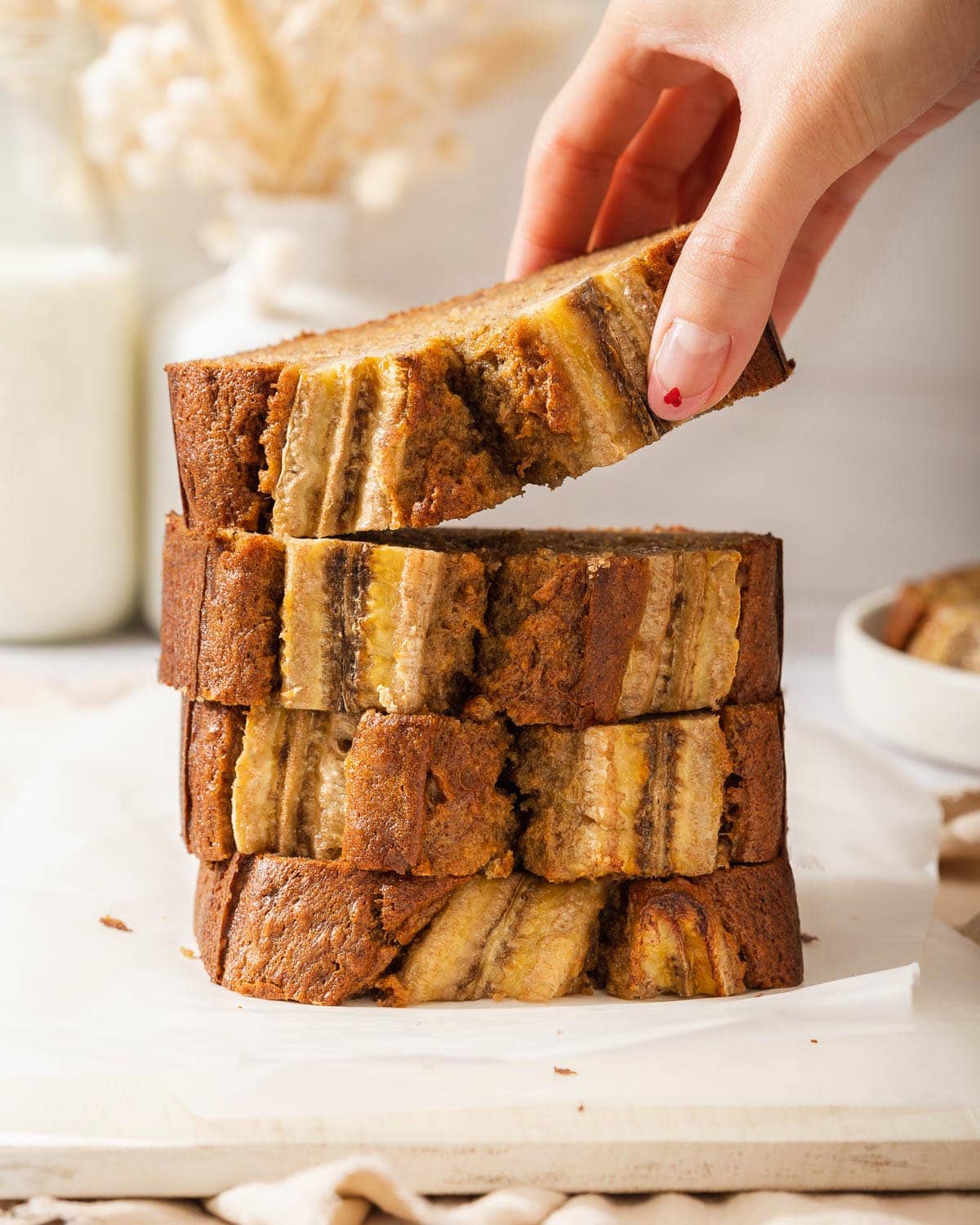 Someone lifting a slice of miso banana bread from a stack of slices.