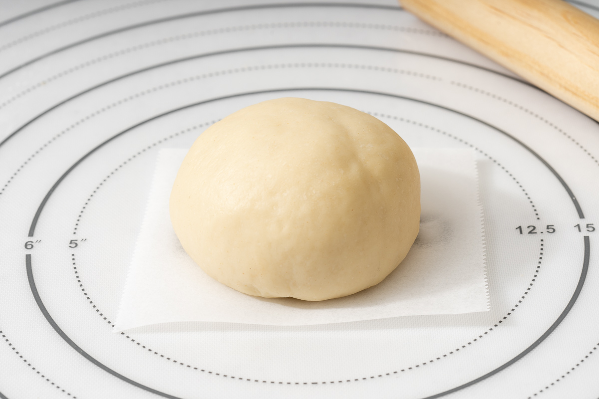 A chocolate filled bun on parchment paper ready for steaming.
