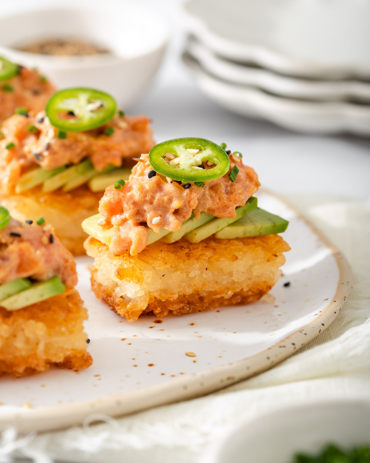 A close up of a spicy tuna crispy rice on an appetizer plate with more crispy rice.