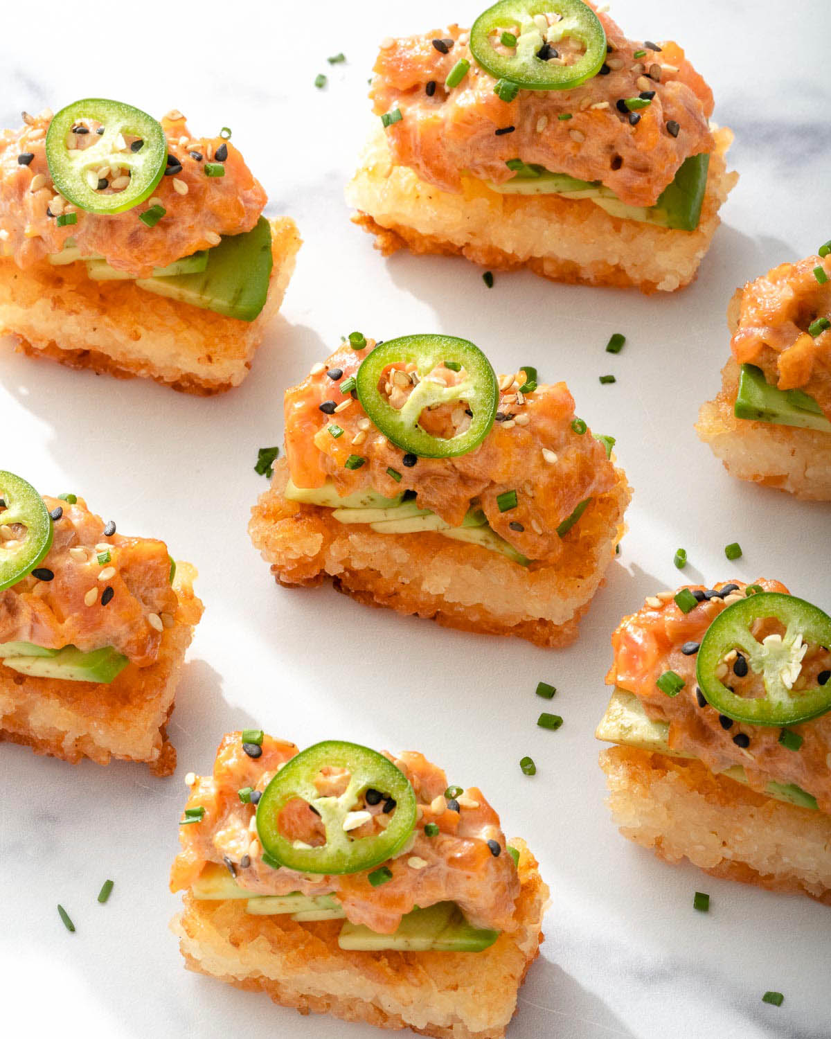 Looking down at a grid of spicy tuna crispy rice cake bites ready for serving.