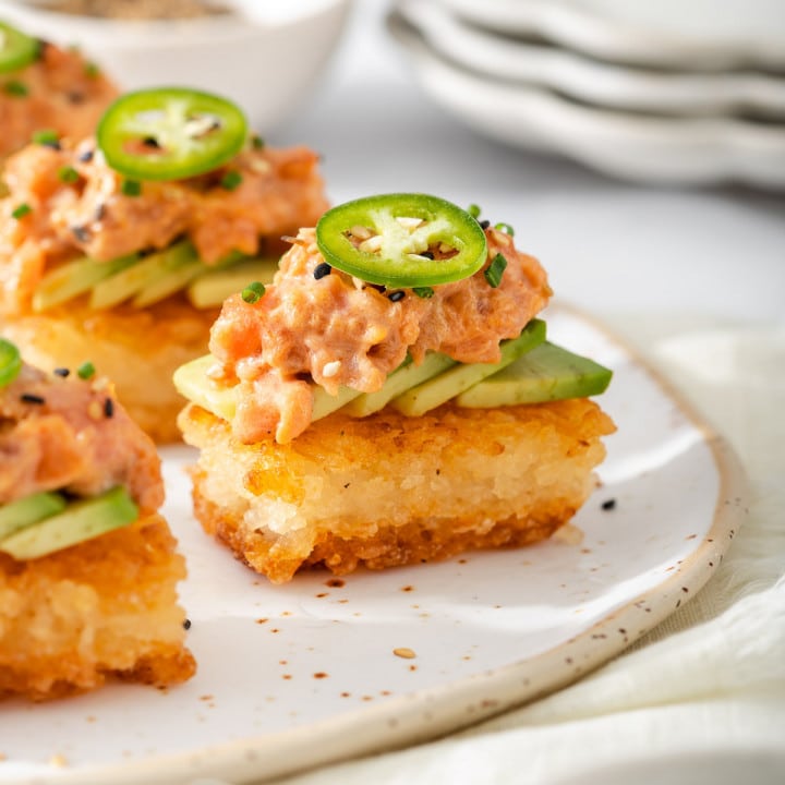 Up close of a plate of mini crispy rice bites topped with spicy tuna.