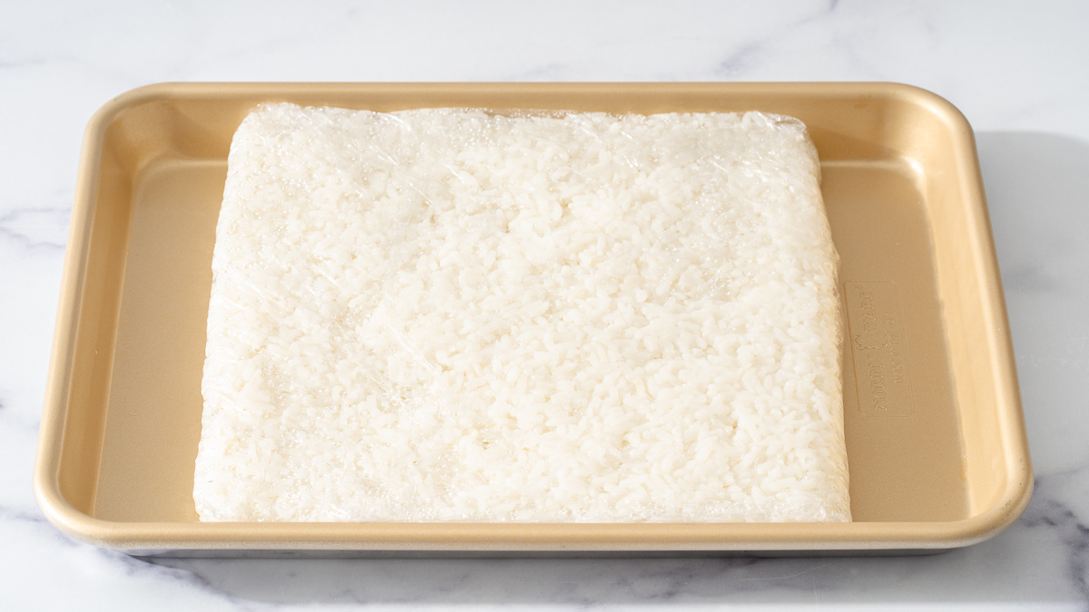 Rice formed into a flat square and wrapped with plastic wrap to chill and dry.