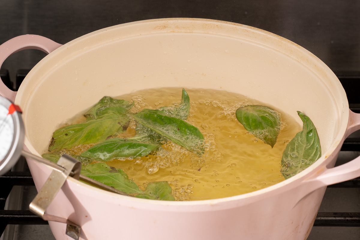 Flash frying basil leaves in oil before frying Taiwanese chicken.