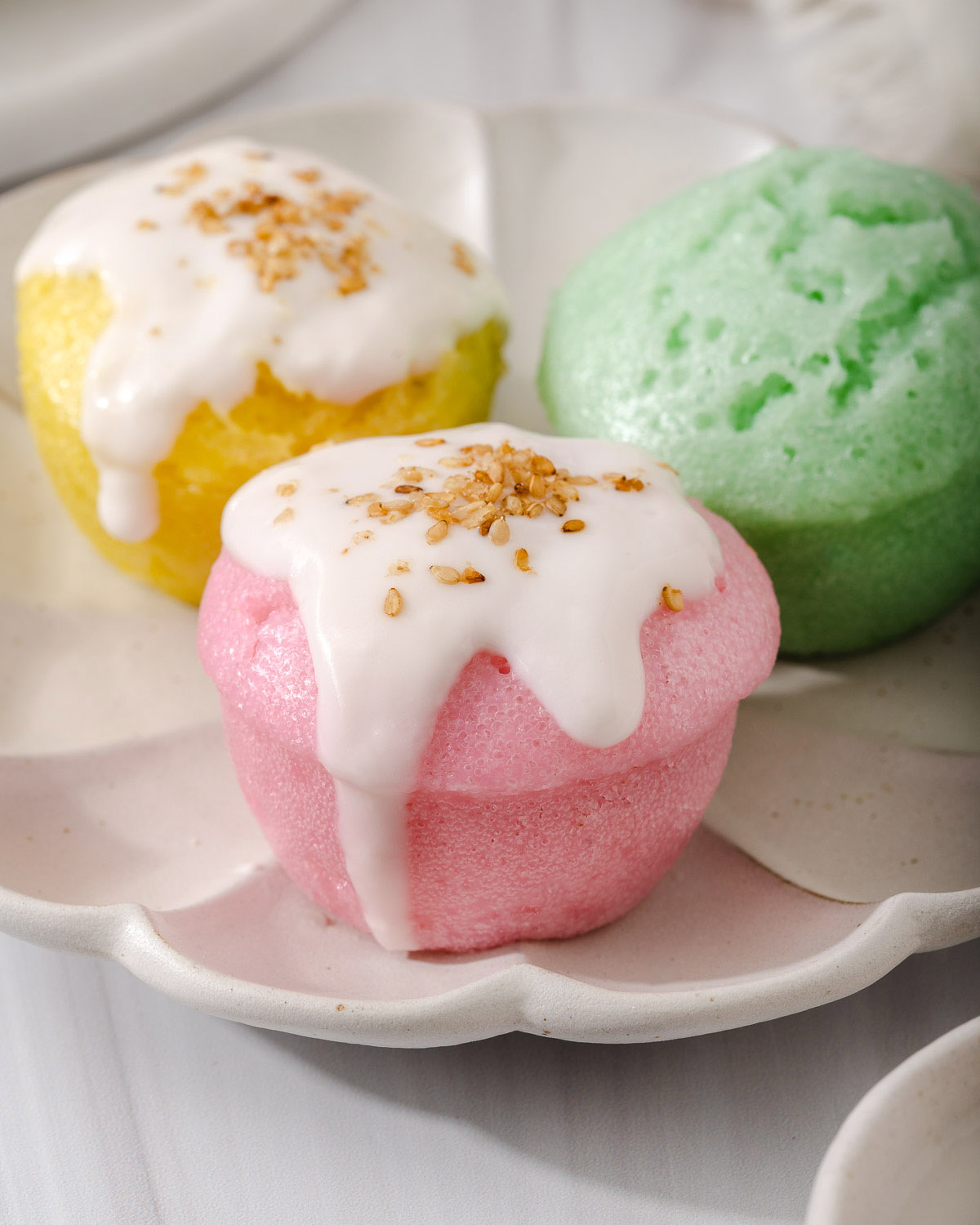 Up close of colorful Vietnamese steamed rice cakes with a coconut cream sauce and sesame seeds.