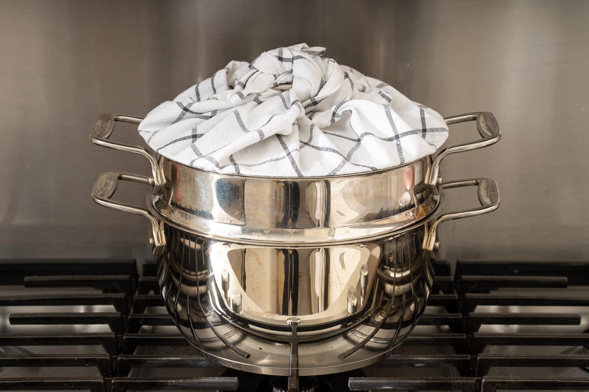 A metal steamed with the lid wrapped in a linen to prevent condensation from dripping.