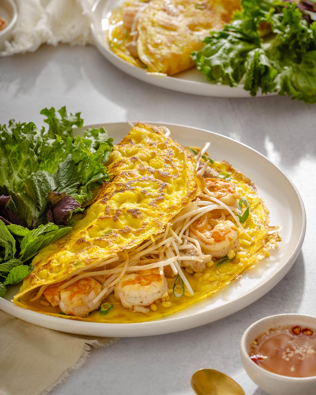 A close up of a plate with bánh xèo and herbs.