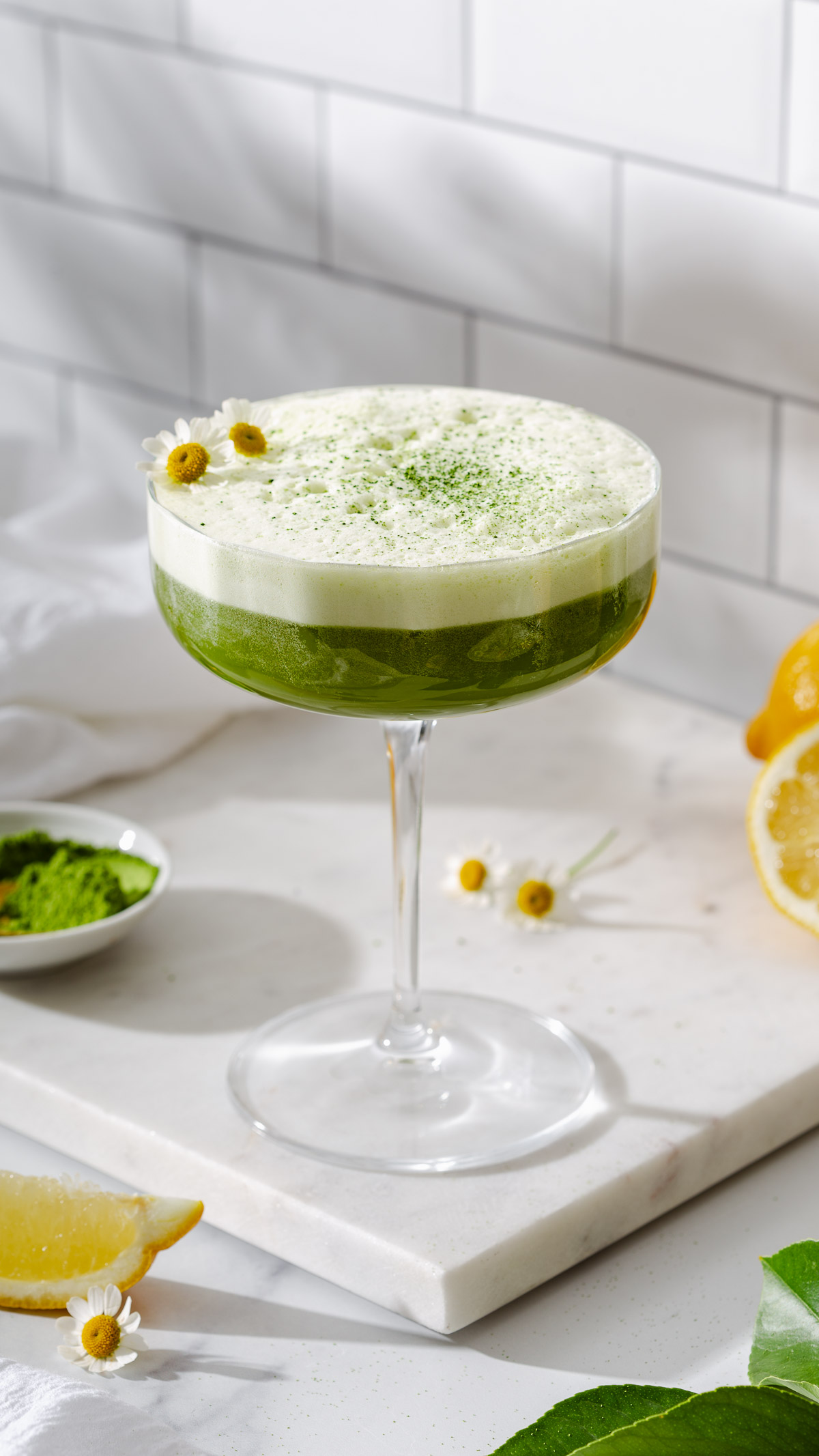 A matcha gin sour in a cocktail glass on a marble counter.