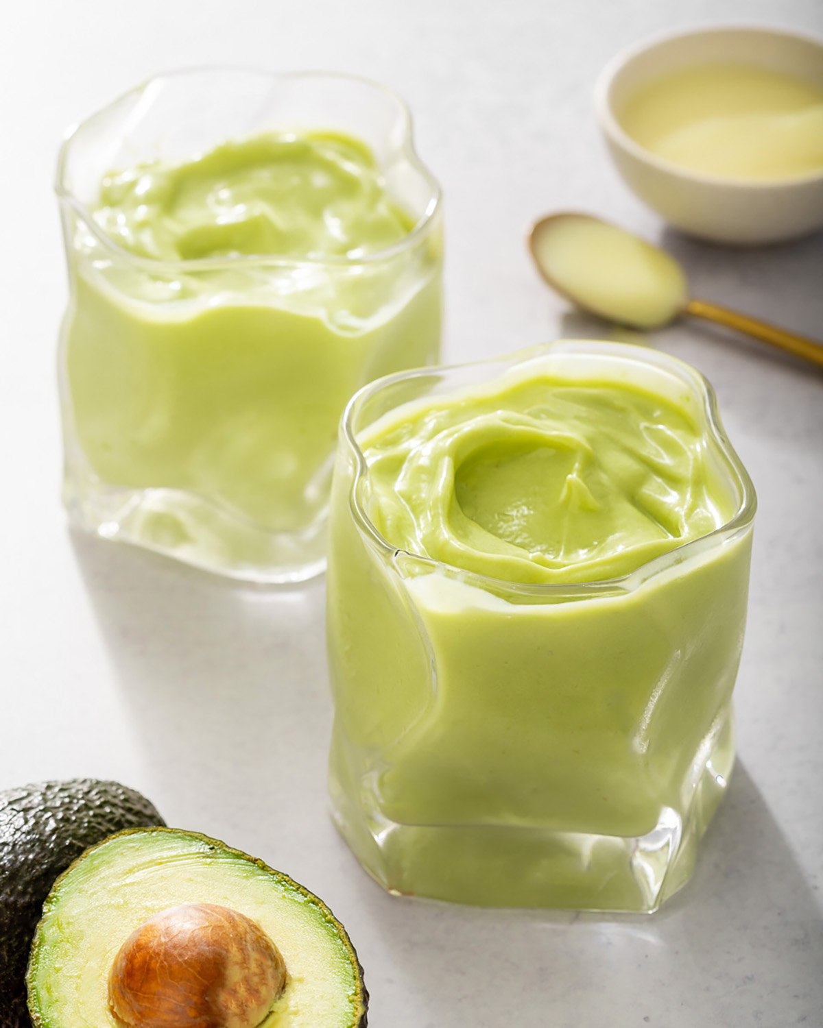 Two glasses with avocado smoothie prepared.