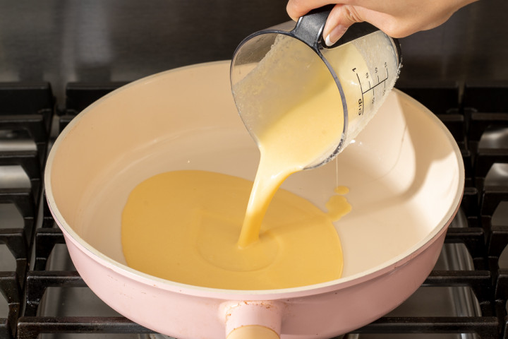 Pouring the batter into a skillet to cook.