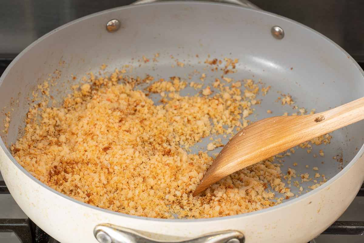 Minced shrimp being cooked in large pan until dried and golden brown.