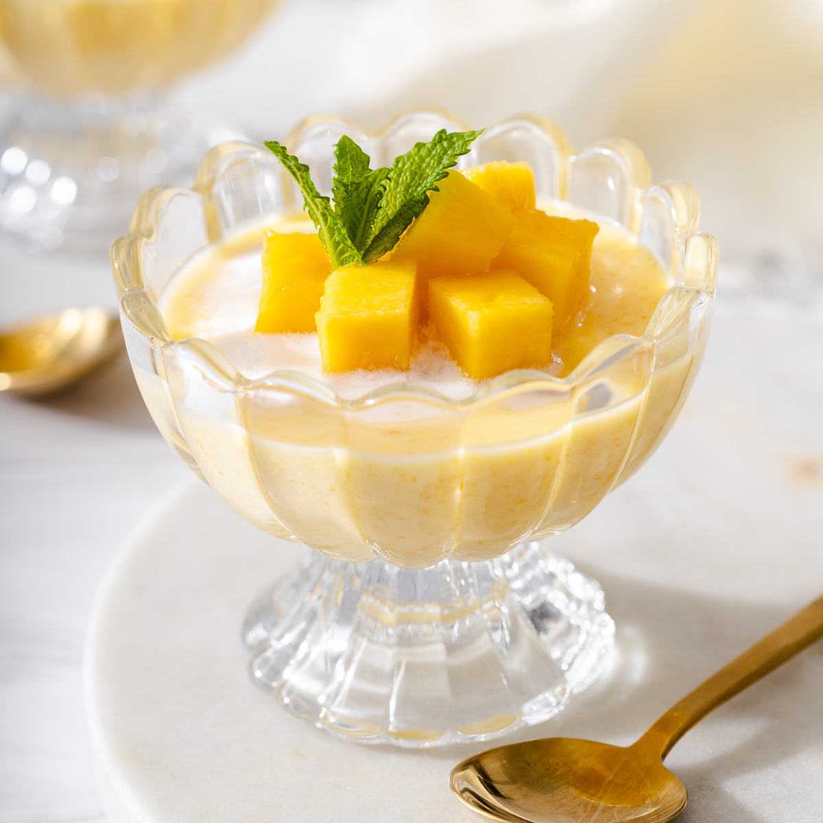 Up close of a small dish of mango pudding topped with fresh mango.