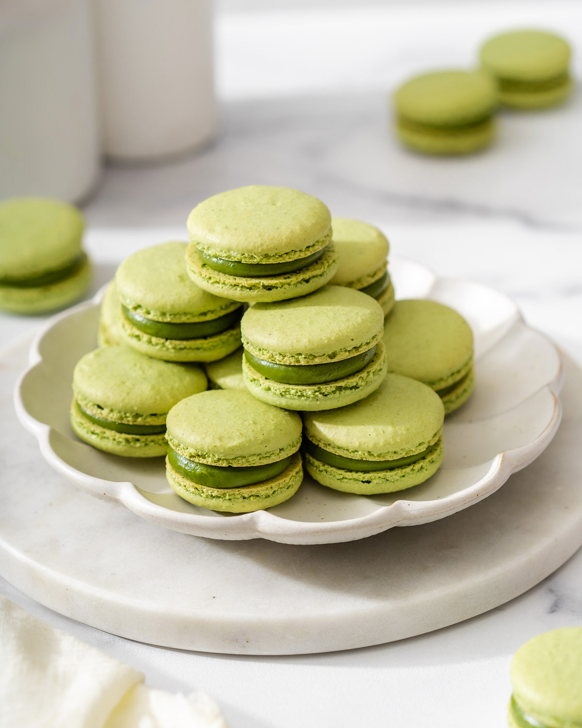 A plate of matcha macarons on a marble serving tray.