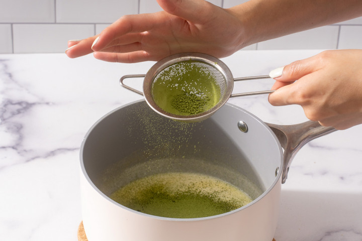 Sifting matcha into the heated heavy cream for a ganache.