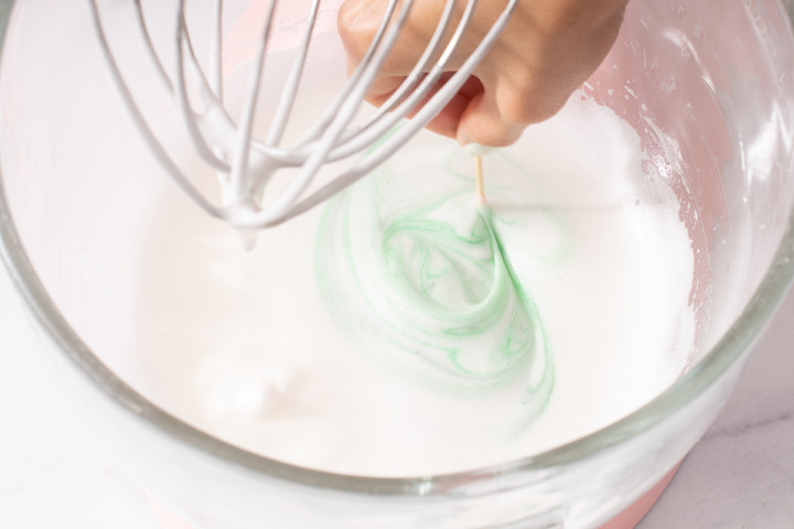 Adding food gel coloring to the whipped meringue.